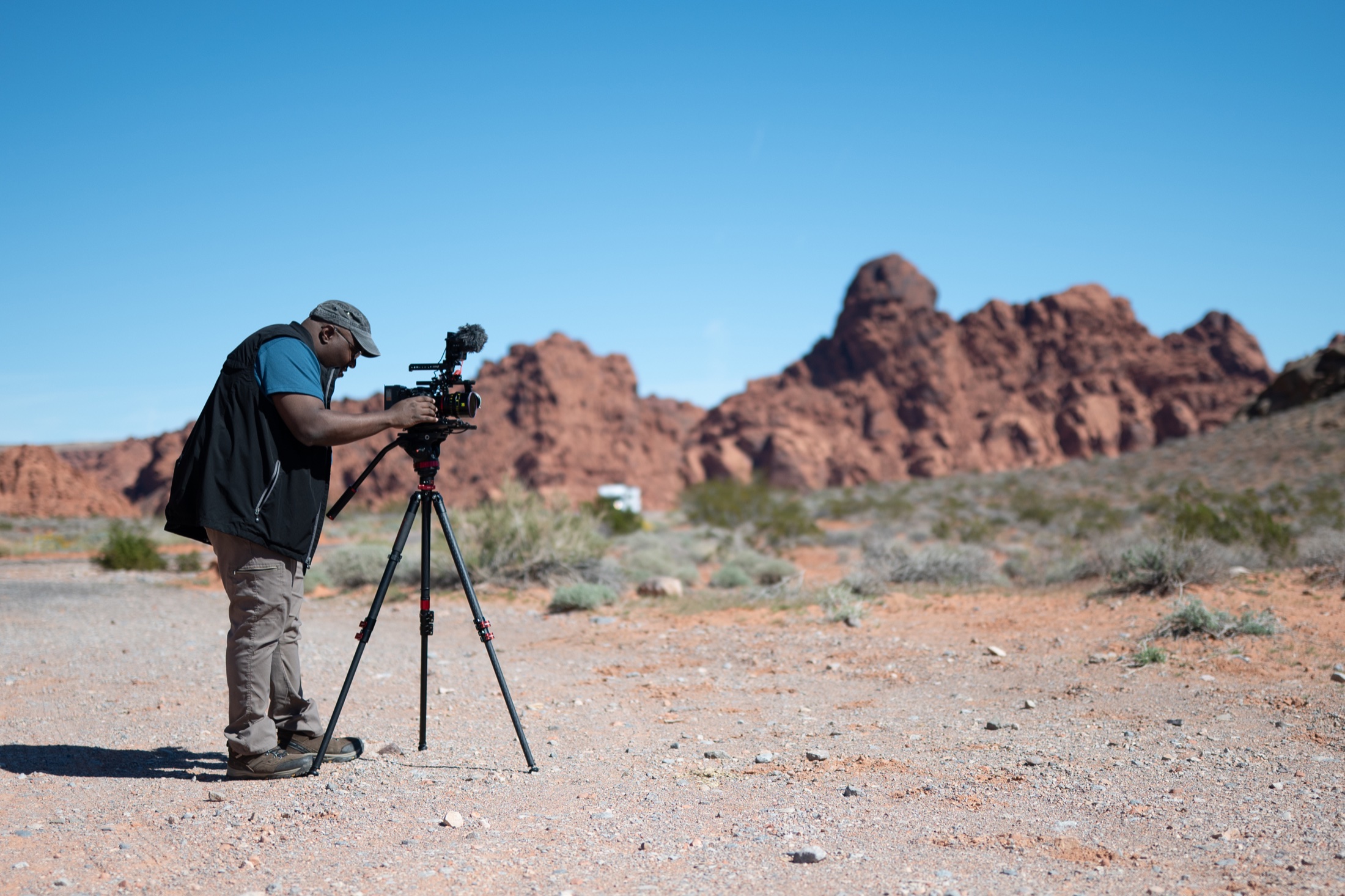 Thomas filming with his cinema camera among desert red rock formations